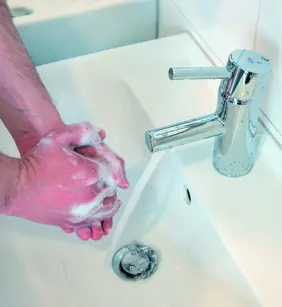 Hände werden mit Seife unter fließendem Wasser an einem Waschbecken gewaschen.